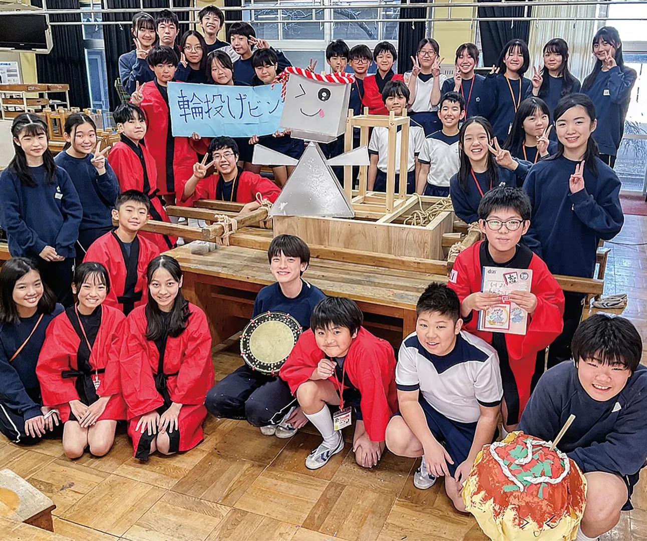 「地域の人たちに喜んでもらいたい」と作成中の神輿やマスコットキャラクターを囲んで笑顔を見せる児童たち。商店街店舗のPRにもつなげるため神輿の周りには加盟店舗の名前を掲げる予定だ
