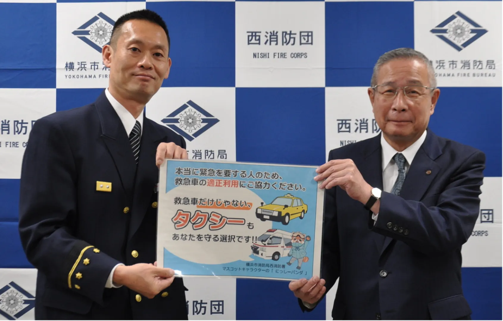 ステッカーの拡大版を持つ石黒署長（左）と市川隆弘取締役業務部長