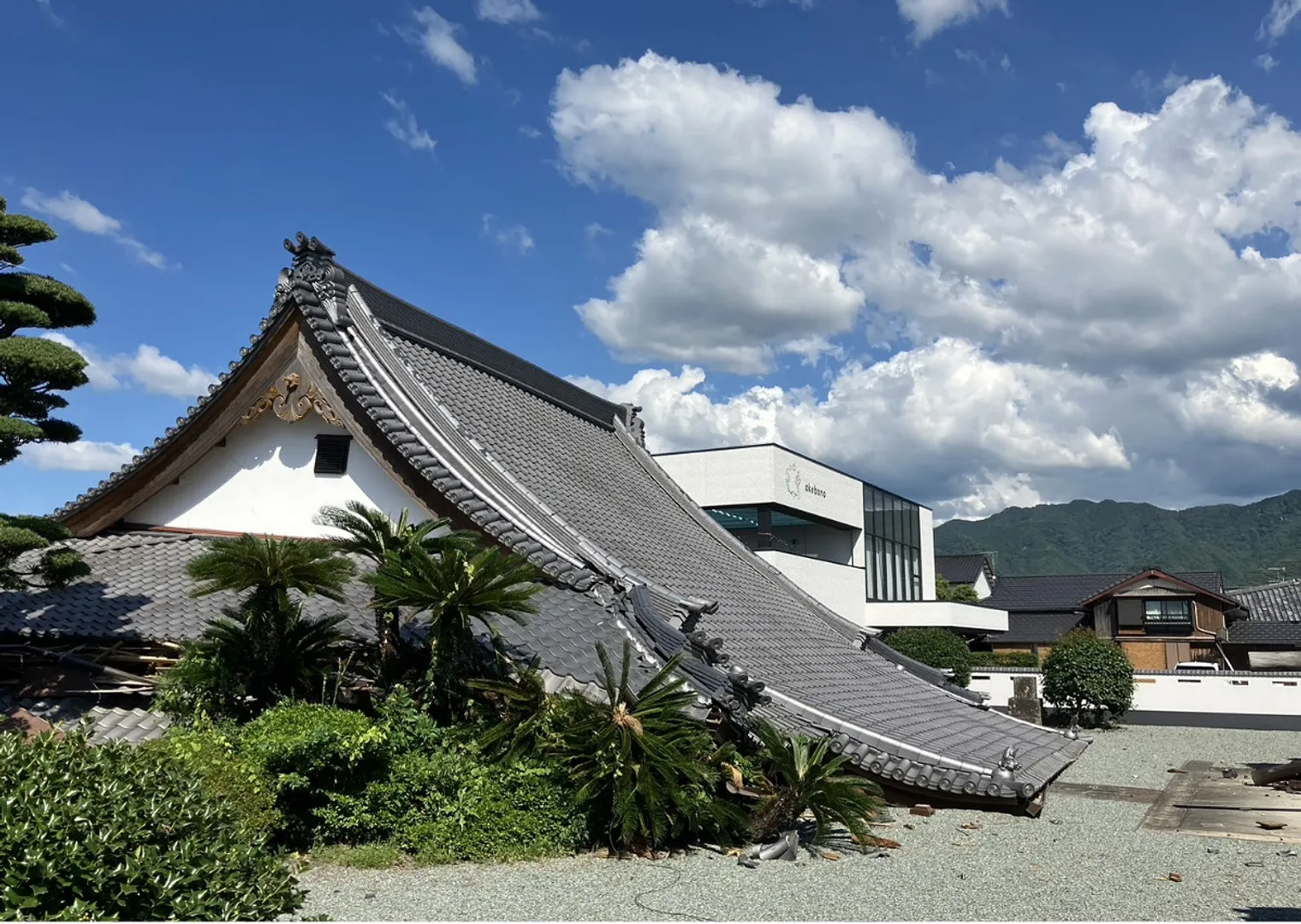 被災地の様子。保育園（白い建物）隣の寺が倒壊＝園長会提供