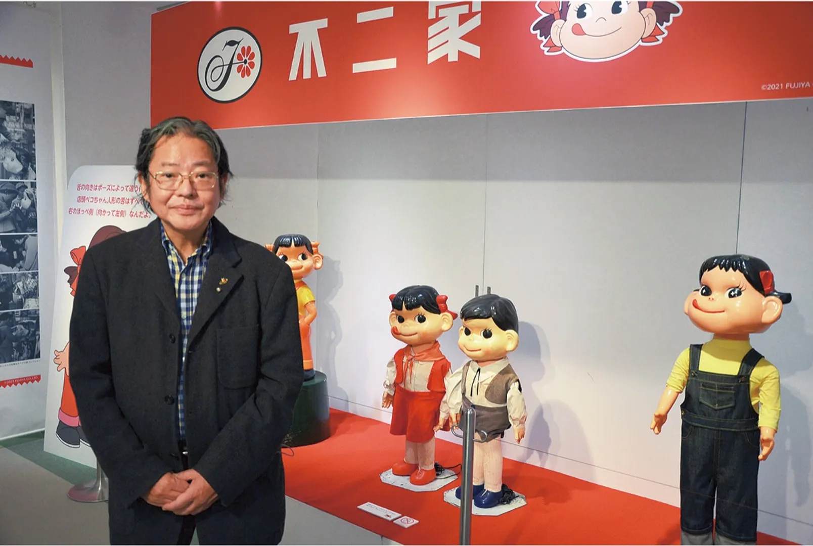 多くのコレクションを提供した本展アドバイザーの新関さんと、展示会場の入り口に飾られた歴代のペコちゃん＆ポコちゃん人形