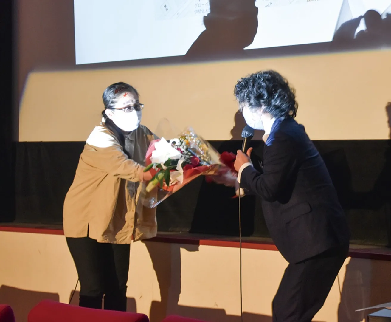 同じミニシアター、横浜シネマリンの八幡温子支配人から花束を受け取る梶原支配人（右）