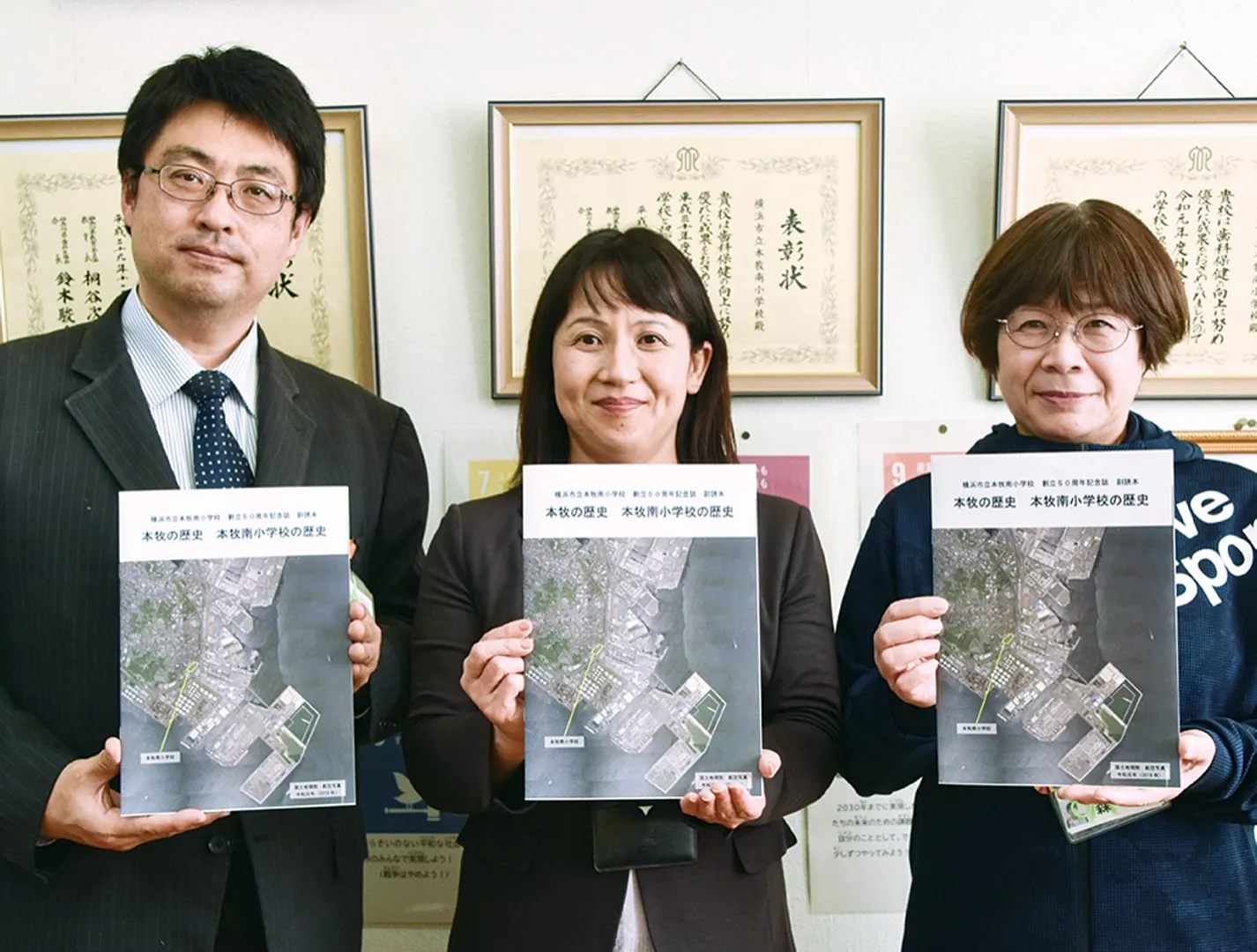 完成した歴史本を手にする谷口校長（中央）と森教諭（右）、針持拓郎副校長