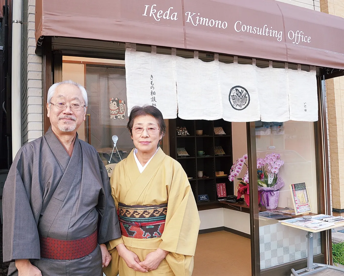 本牧通り沿いの上野町バス停前にオープンした「きもの相談処 いけ田」＝中区上野町１の29＝の前で池田さん夫妻