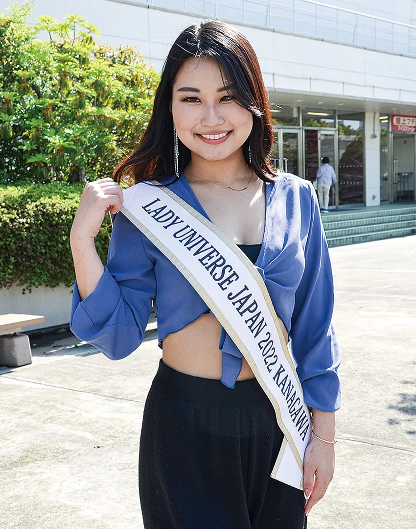 レディー・ユニバース・ジャパンのたすきをかけほほ笑む藤野さん