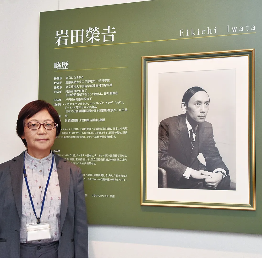 岩田を紹介するパネルの前に立つ武田理事長