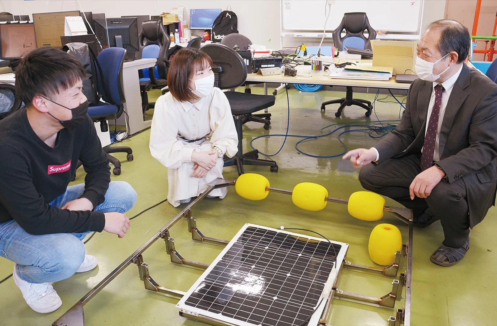 海中ソーラー発電システムを前に話し合う由井教授（写真右）と学生