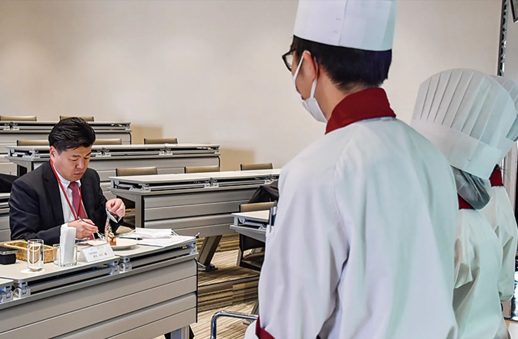学生考案のケーキを食す審査員