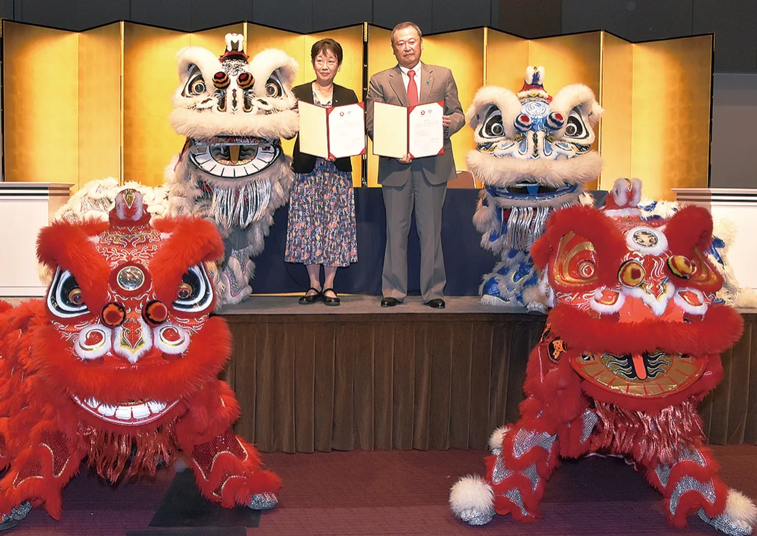４体の獅子とともに協定書を手にする高橋理事長（右）と額田社長