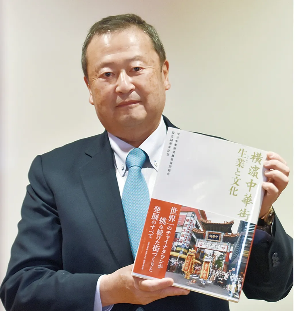 完成した記念誌を手にする高橋理事長