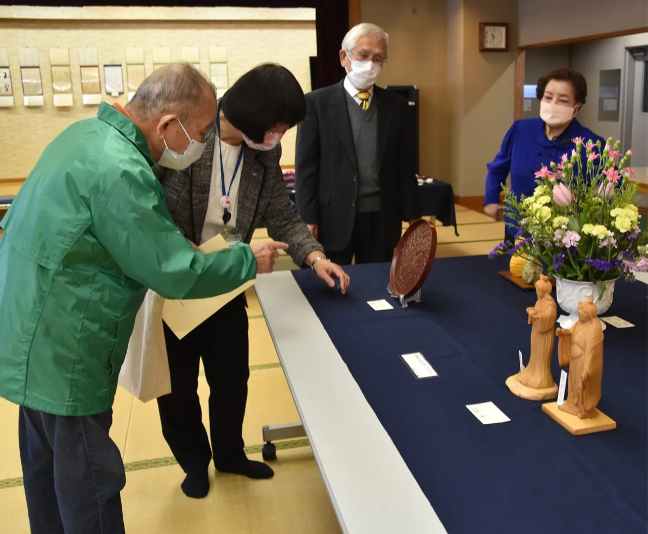 鎌倉彫のお盆について説明を受ける直井中区長（左から２人目）