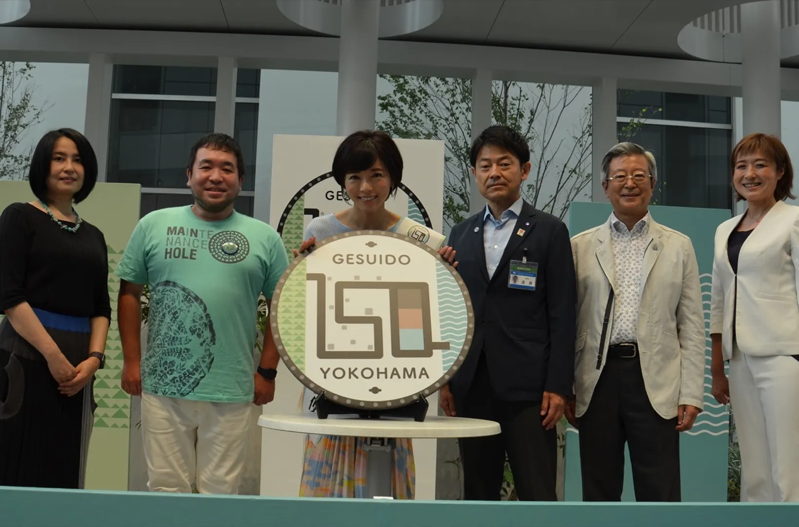 150周年記念のマンホールレプリカを持つ釈さんと出演者ら