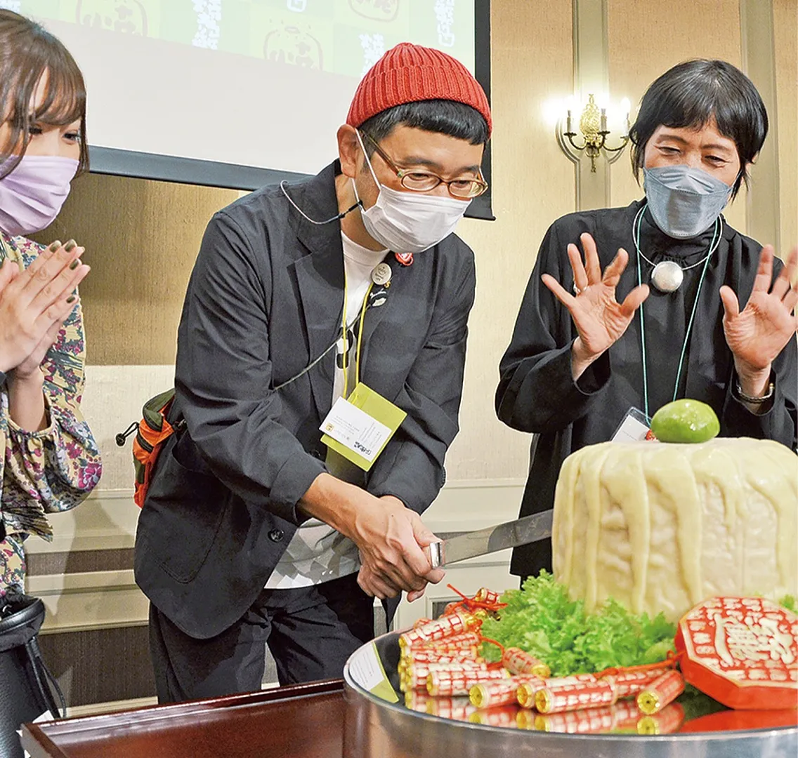 協会の発展を願い、崎陽軒名物のジャンボシウマイに入刀する種藤さん＝中央