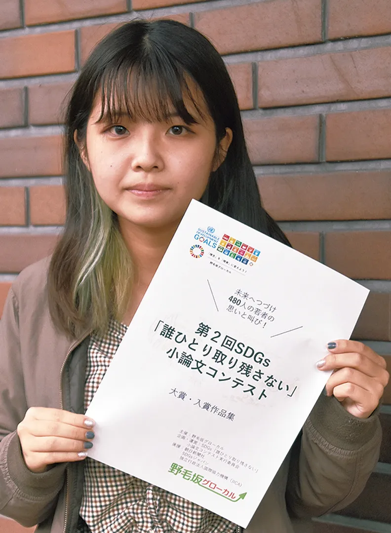 第２回作品集の表紙を手にする共同実行委員長の安藤さん