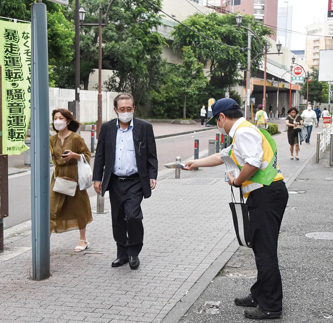 チラシを配る交通安全推進委員＝石川町駅北口前