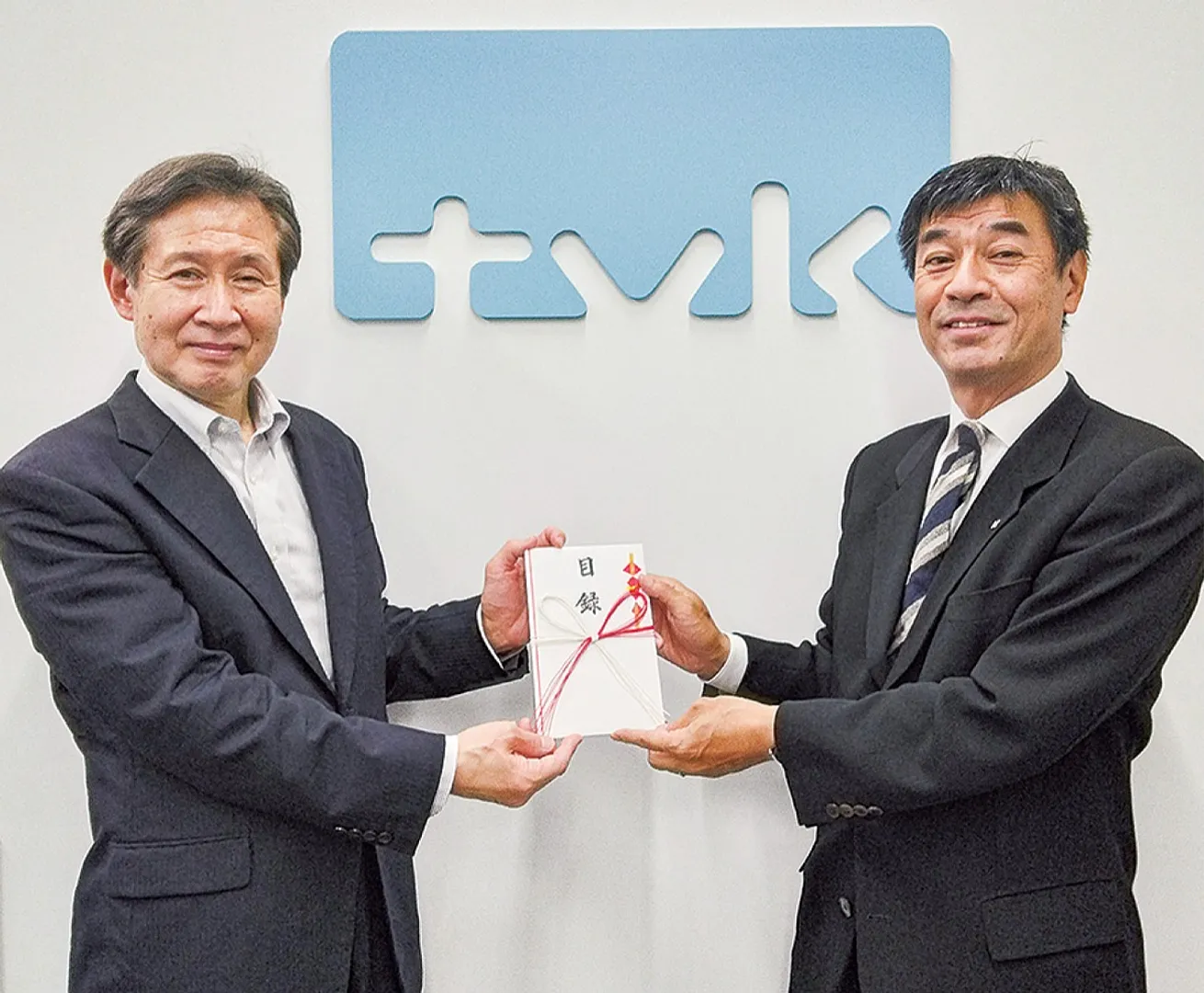 玉村実行委員長（右）から坂井理事長に目録が渡された