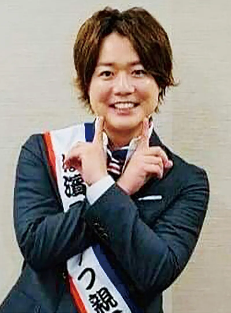 首元にスカーフを巻き、お決まりのポーズでシュウペイさん（上下写真は横浜繊維振興会提供）