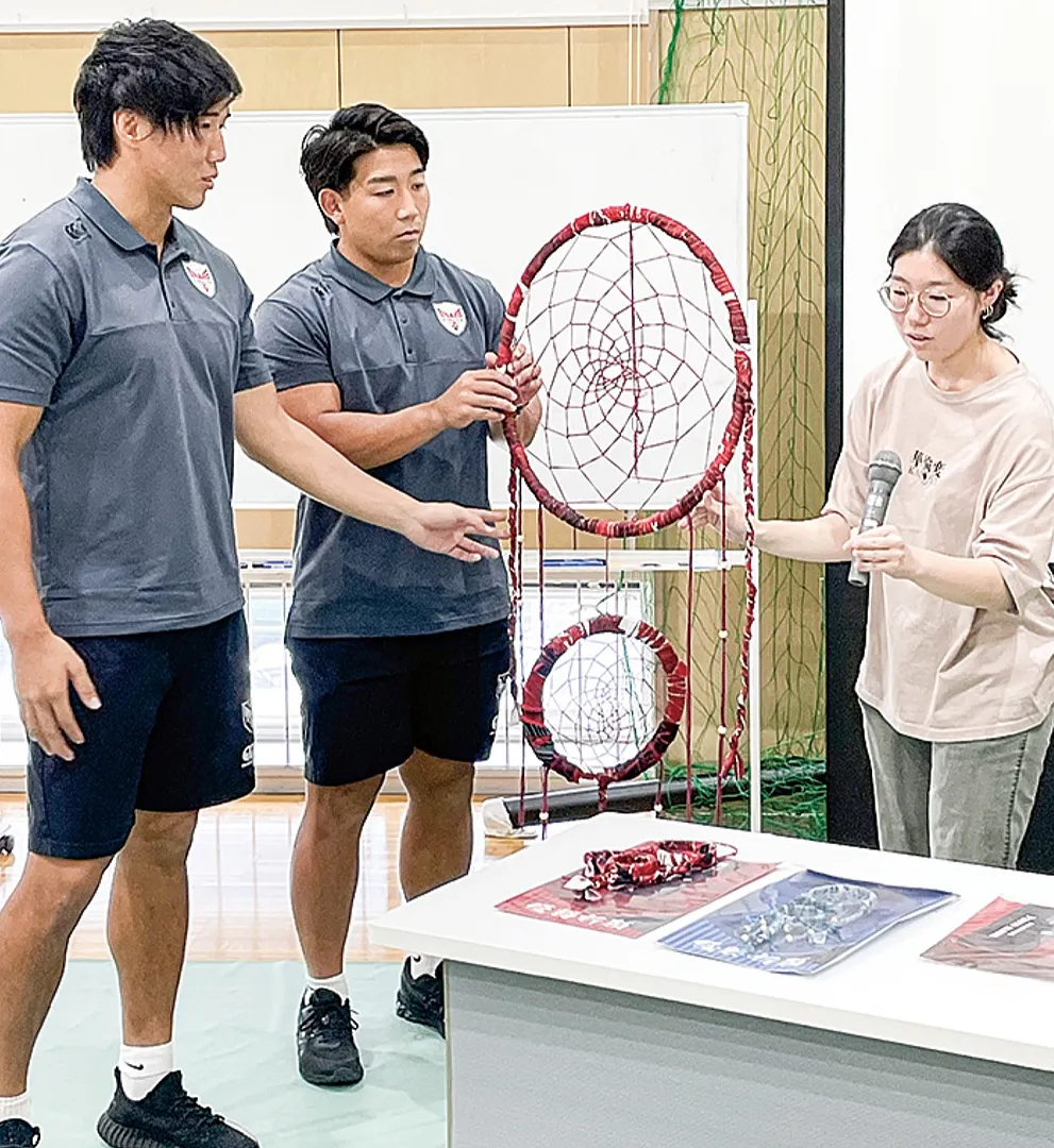 布を巻き付けて製作された｢ドリームキャッチャー｣。学生が選手に説明した