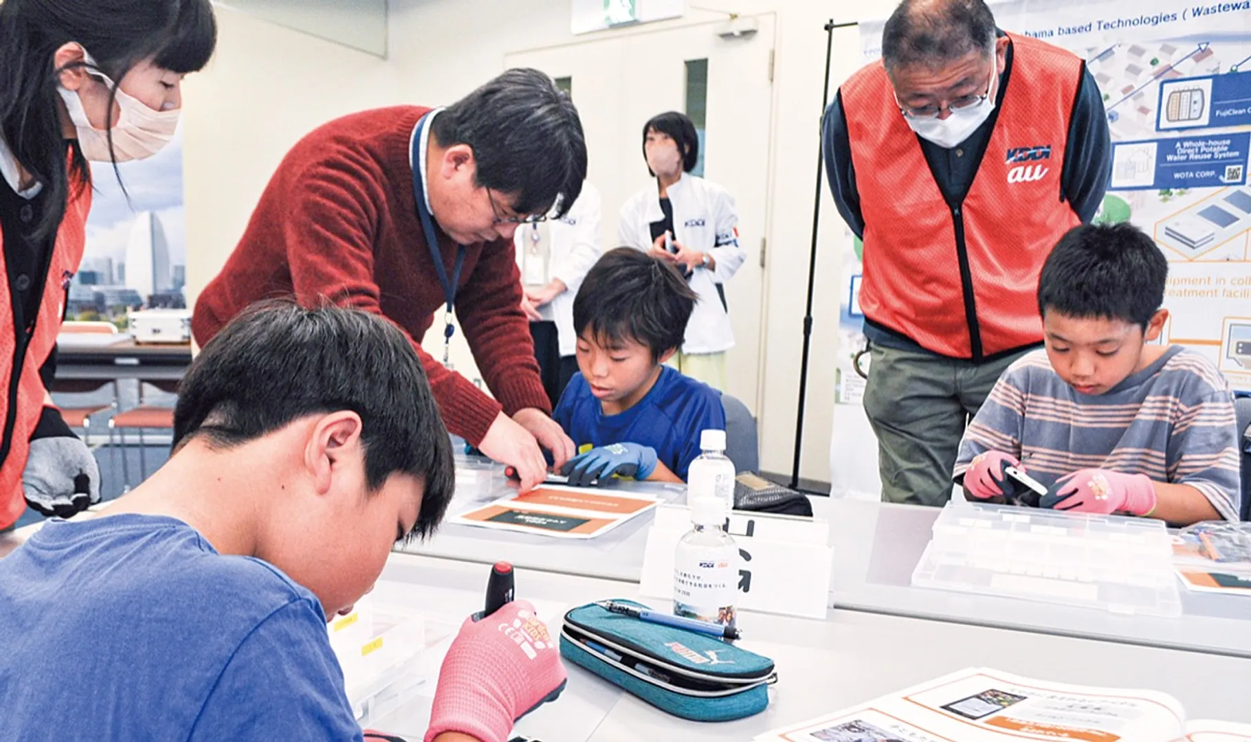 ドライバーを使いスマホを分解する子どもたち