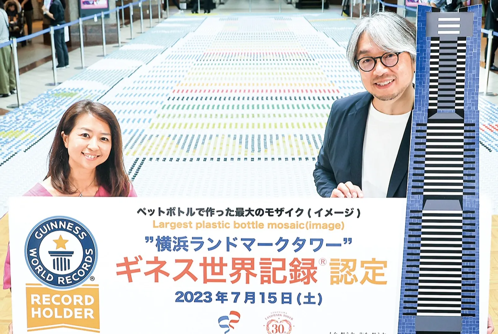 完成したモザイクアートを前にする小山さん（右）と柳井麻希さん＝ランドマークプラザ提供