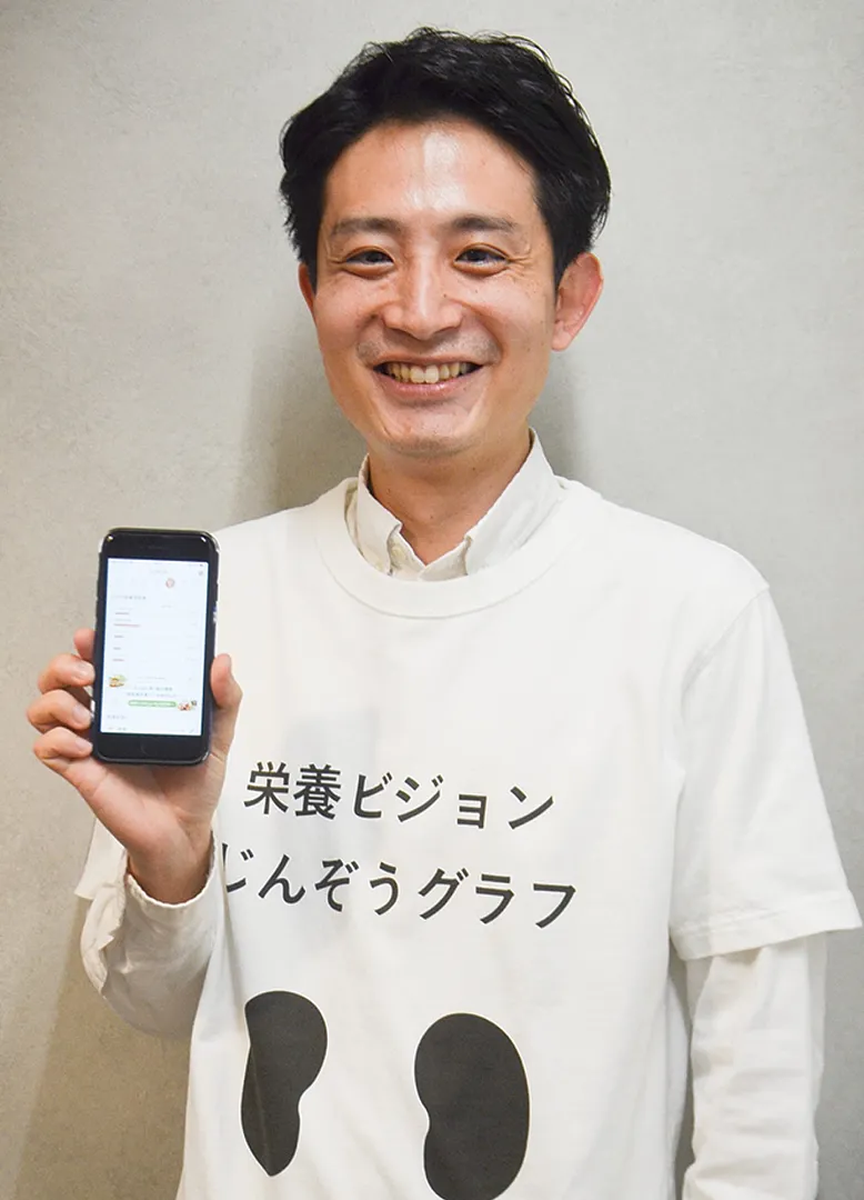 アプリ画面を見せる松岡社長