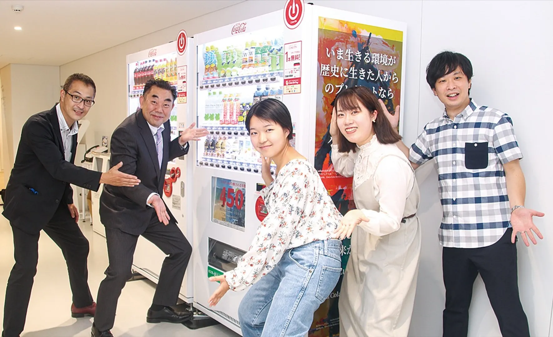 ポスターて掲示した自販機前でルカリス（女性２人）と山本支店長（左から２番目）ら