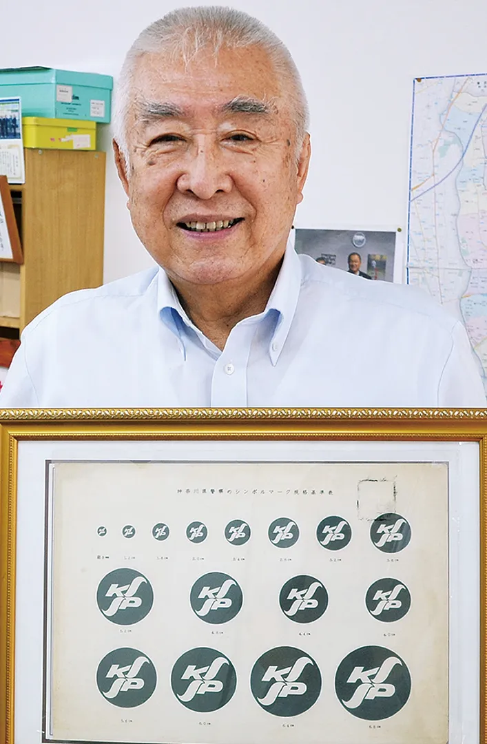 県警のシンボルマークを手に伊藤さん。退職後は地元で柔道場を開き、自身は8段。防犯教室なども行っている